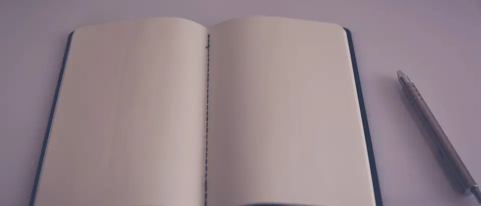 An open notebook with blank pages and a pen