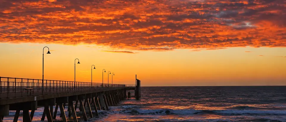 The jetty at Glenelg at sunset, its lamps in a row against an orange sky
